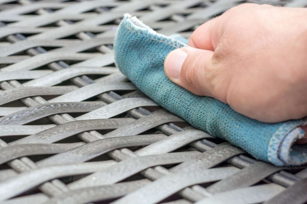 Man wiping down rattan outdoor furniture