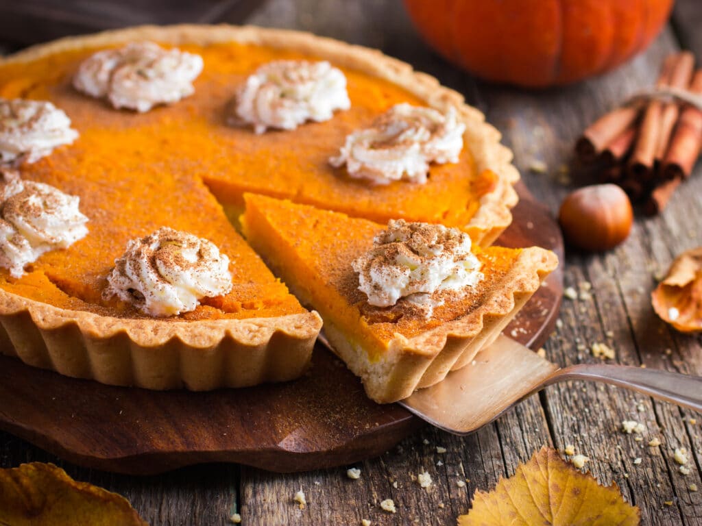 Delicious pumpkin pie being cut on a table