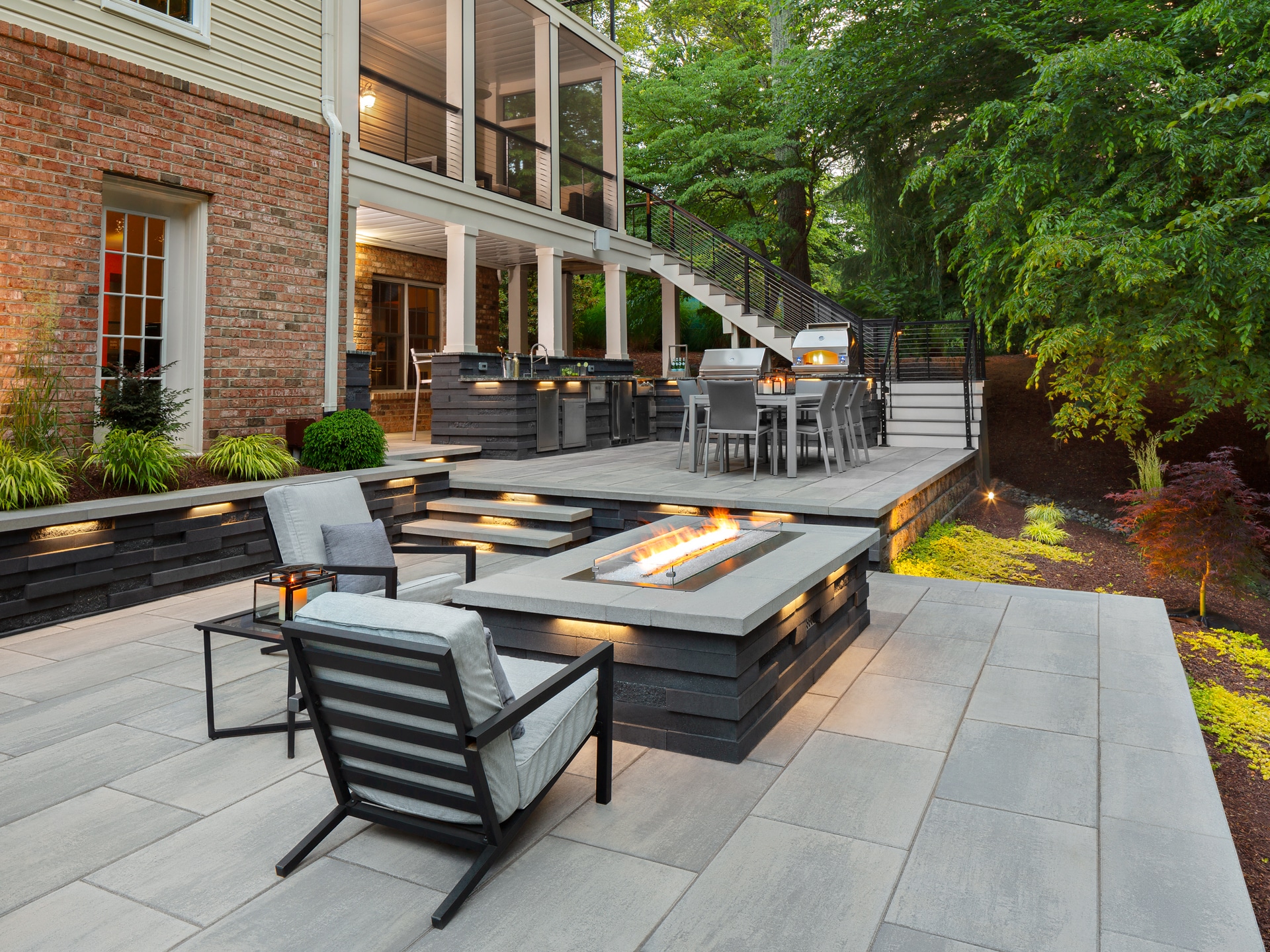 Full outdoor living spacewith kitchen, firetable area, and seating